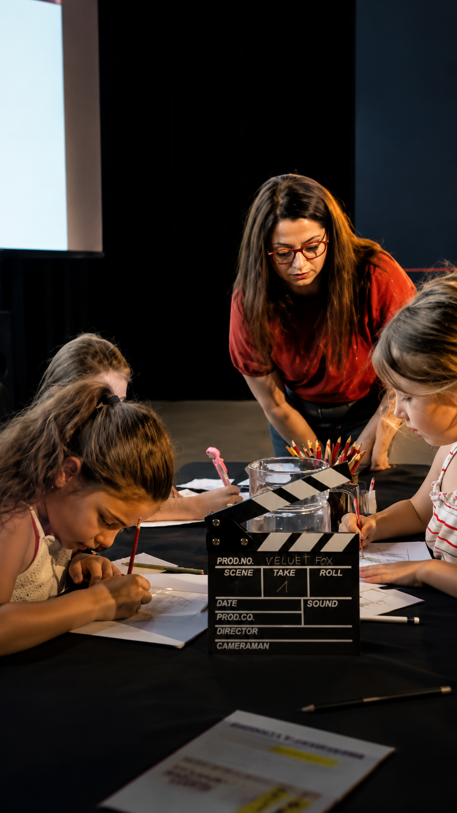 Marlène accompagne des enfants qui dessinent autour du clap Velvet Fox dans une salle de cinéma